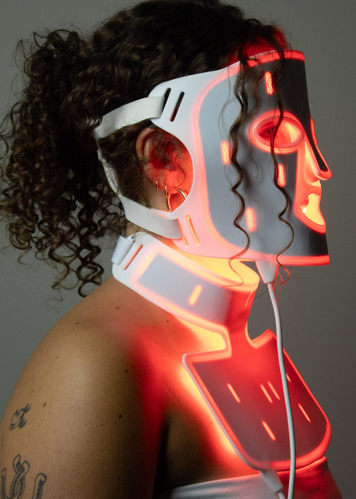 Side profile of PHOS Complete System showing face mask and neck treatment fit with adjustable straps and red LED light therapy