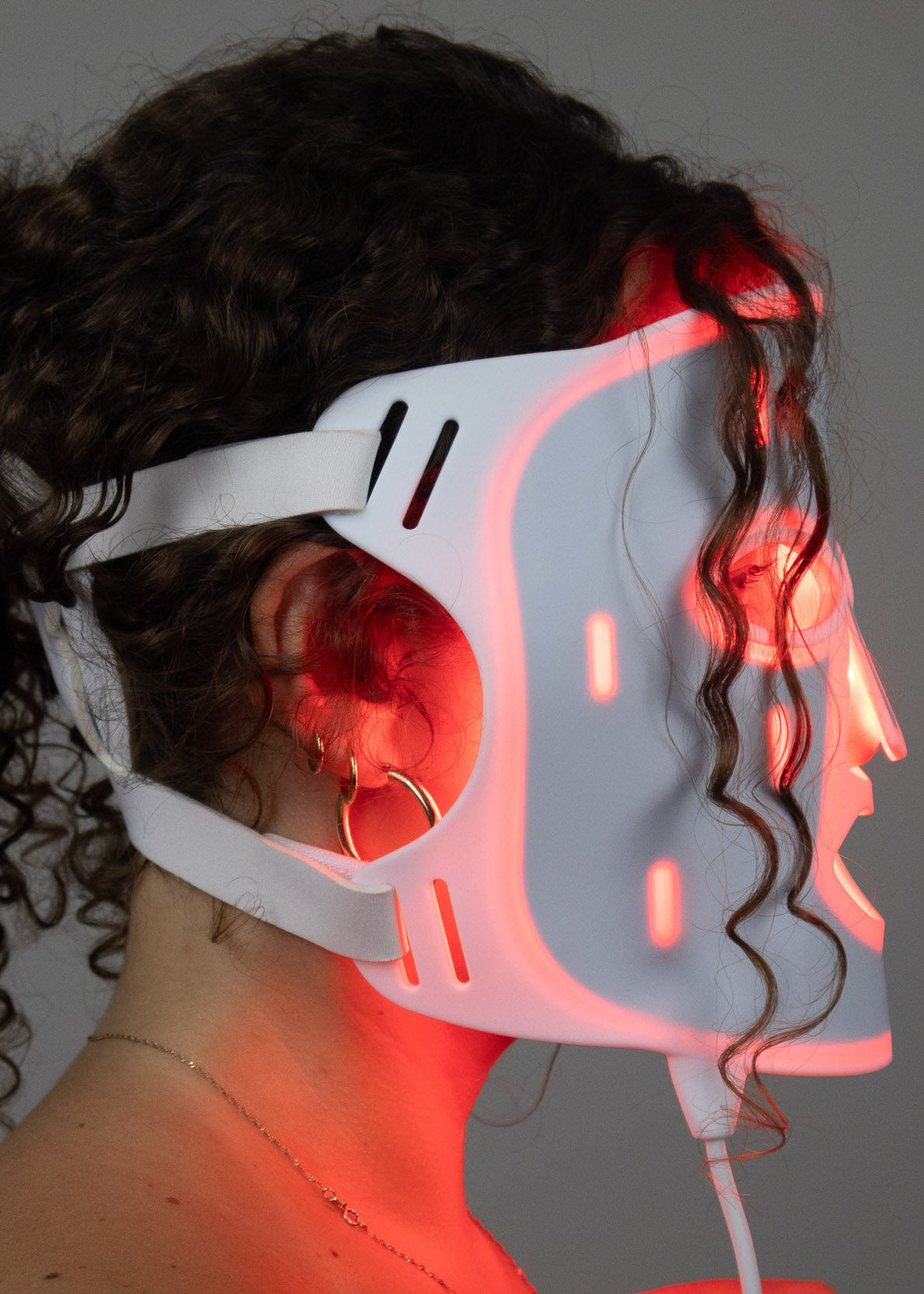 Side profile of PHOS Face Mask showing adjustable elastic straps, medical-grade silicone fit, and red LED light therapy